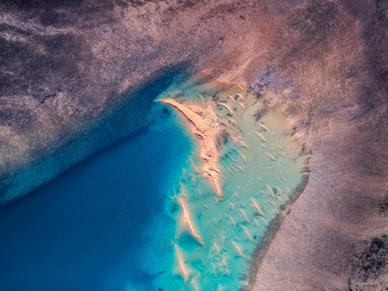 Broken Moon – aerial photograph by Steven Manolakis, showing sharp-edged white sandbars scattered like fragments across blue tidal waters in Western Australia