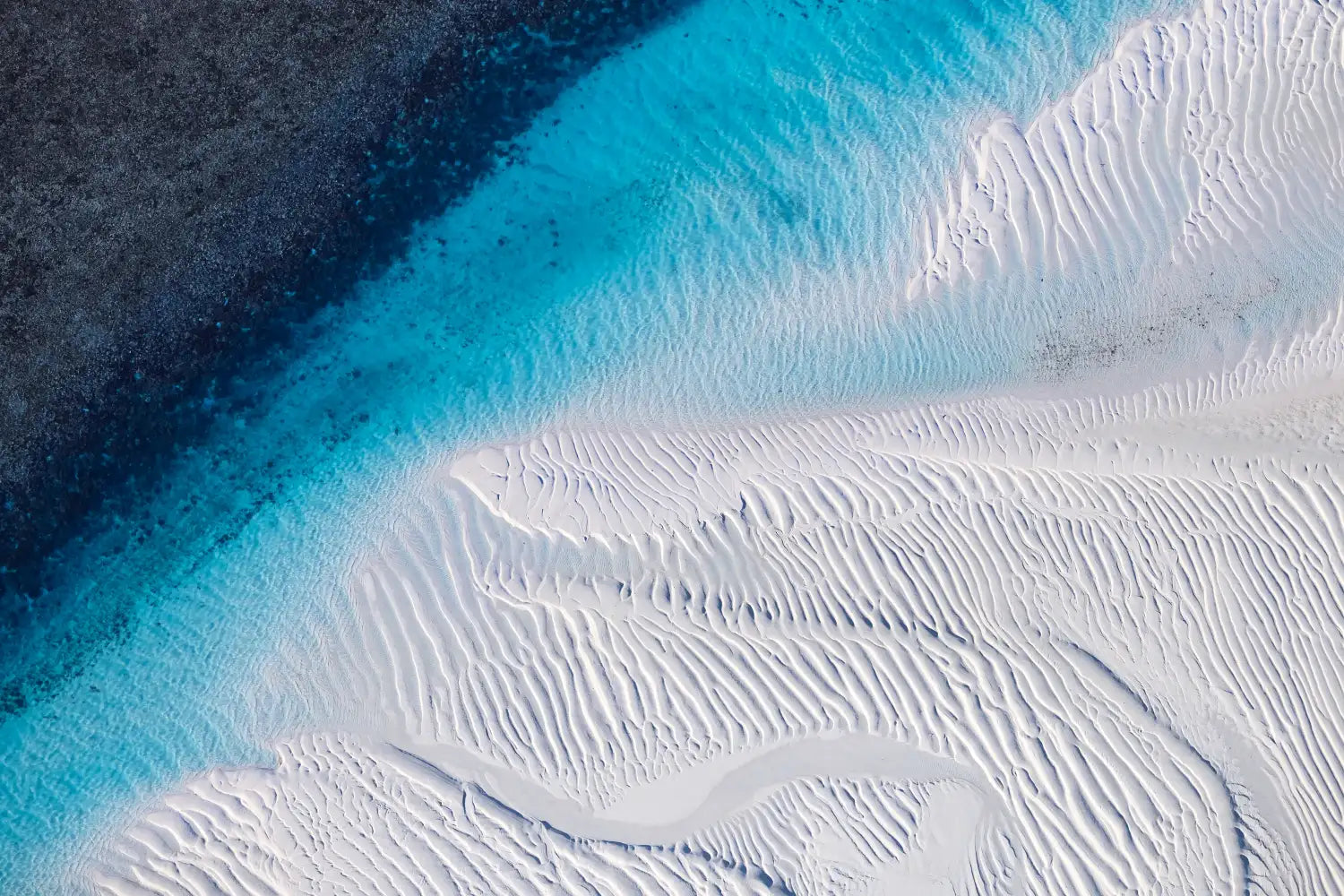 Delicate aerial photo, Kimberley, WA. Sapphire water gradient contrasts white, finely-rippled sand.