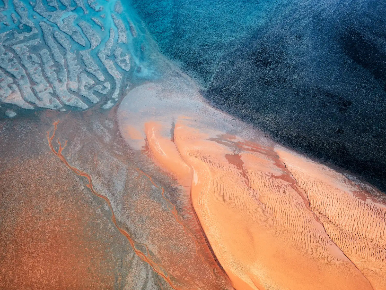 The Expanse – aerial photograph featuring an orange sand dune sprawling into an intricate reef system in the Northern Territory